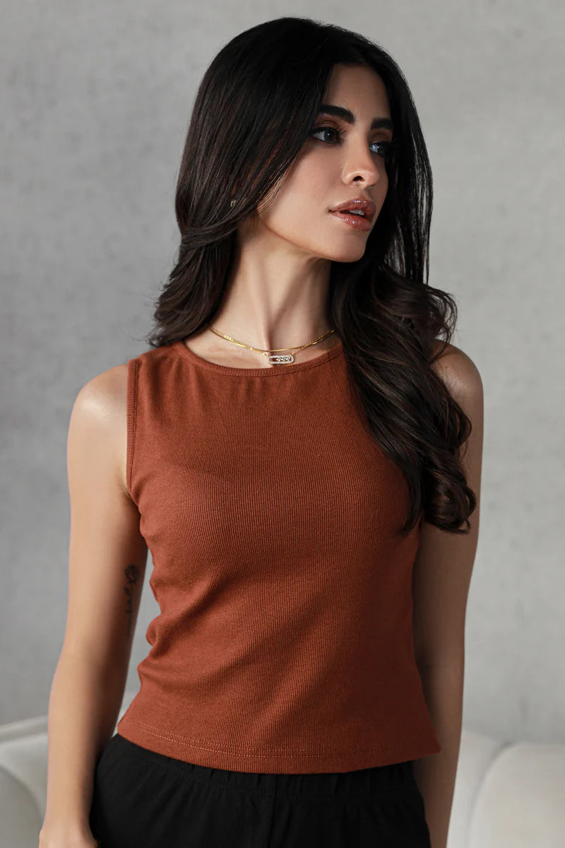  Woman wearing a rust-colored gym tank top for women, showcasing a sleek and minimalistic design perfect for workout wear.